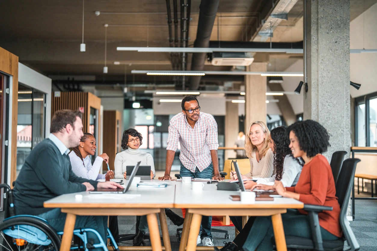 A diverse group of people collaborating around a table, each using a laptop for discussion and teamwork for agile marketing process