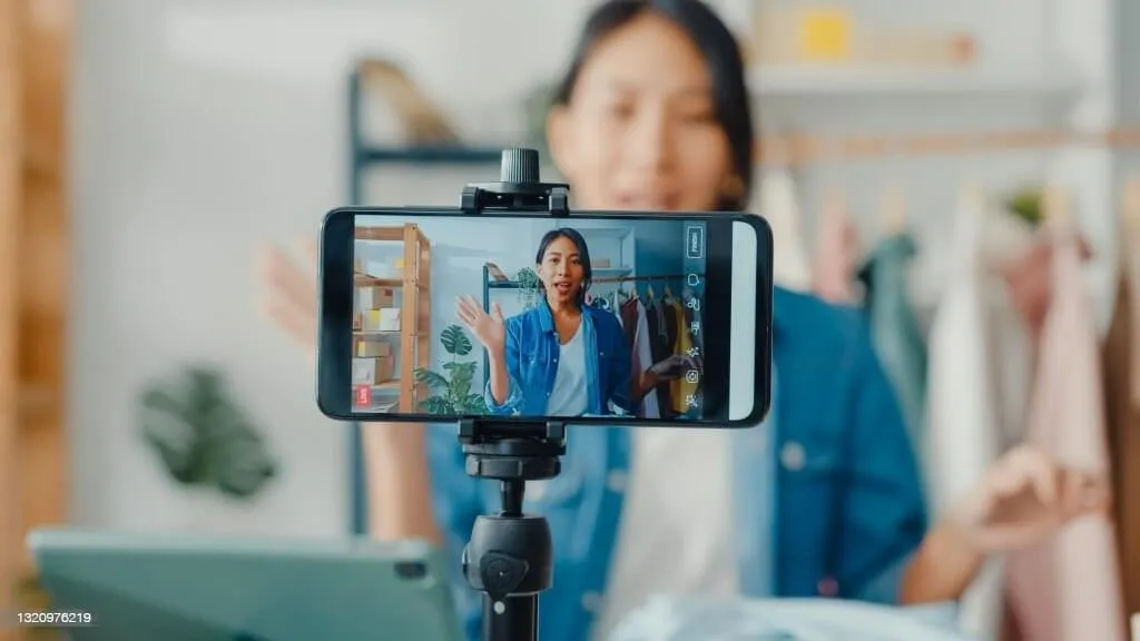 A woman holding a smartphone, engaged in a video call, smiling as she interacts with the screen while working with b2b influencers