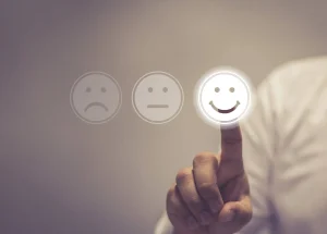 A man smiling while pressing a button featuring a smiley face while customer effort score in b2b