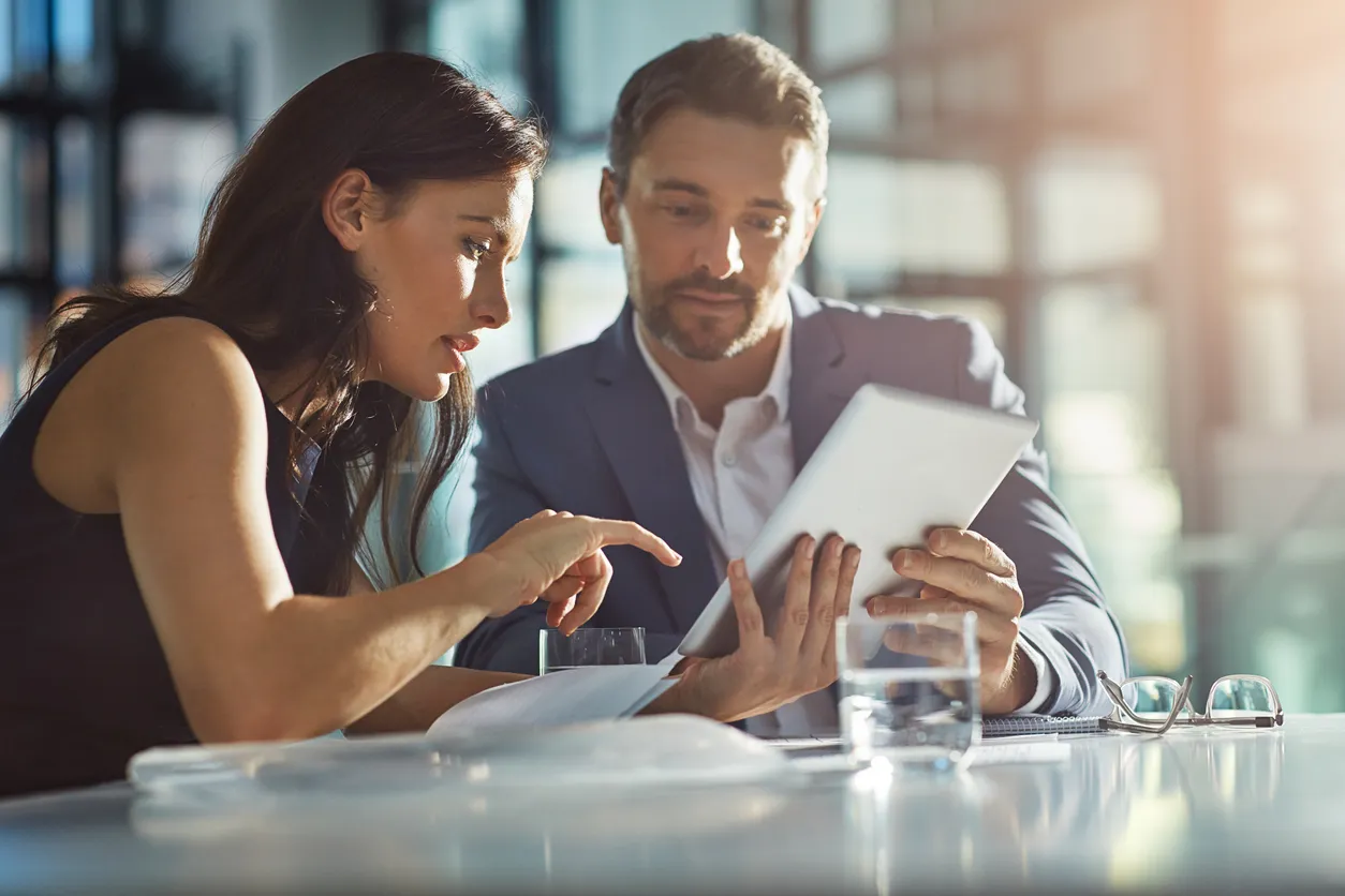 A man and woman are engaged in discussion while looking at a tablet computer together while b2b marketing funnel stages explained