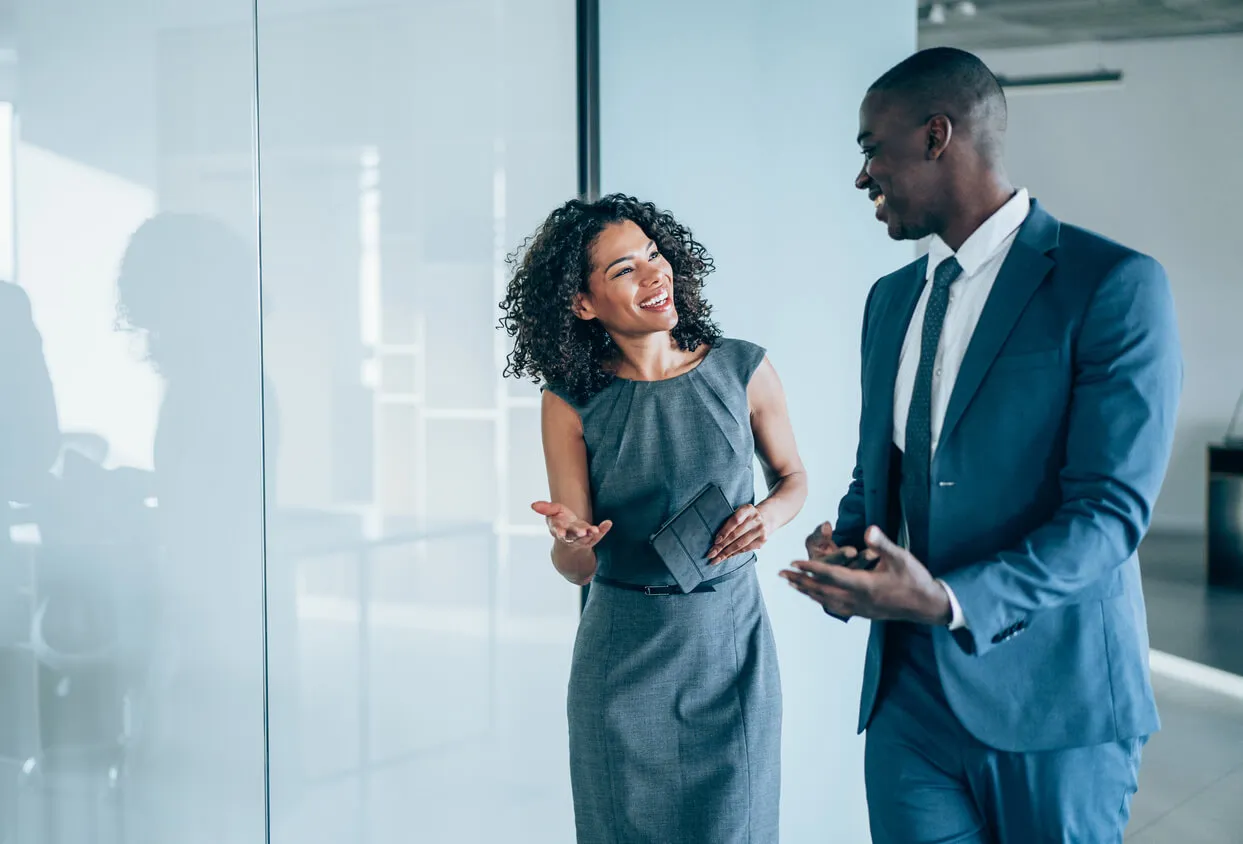 A business couple engaged in conversation in a modern office setting, discussing work-related matters of gated content best practices