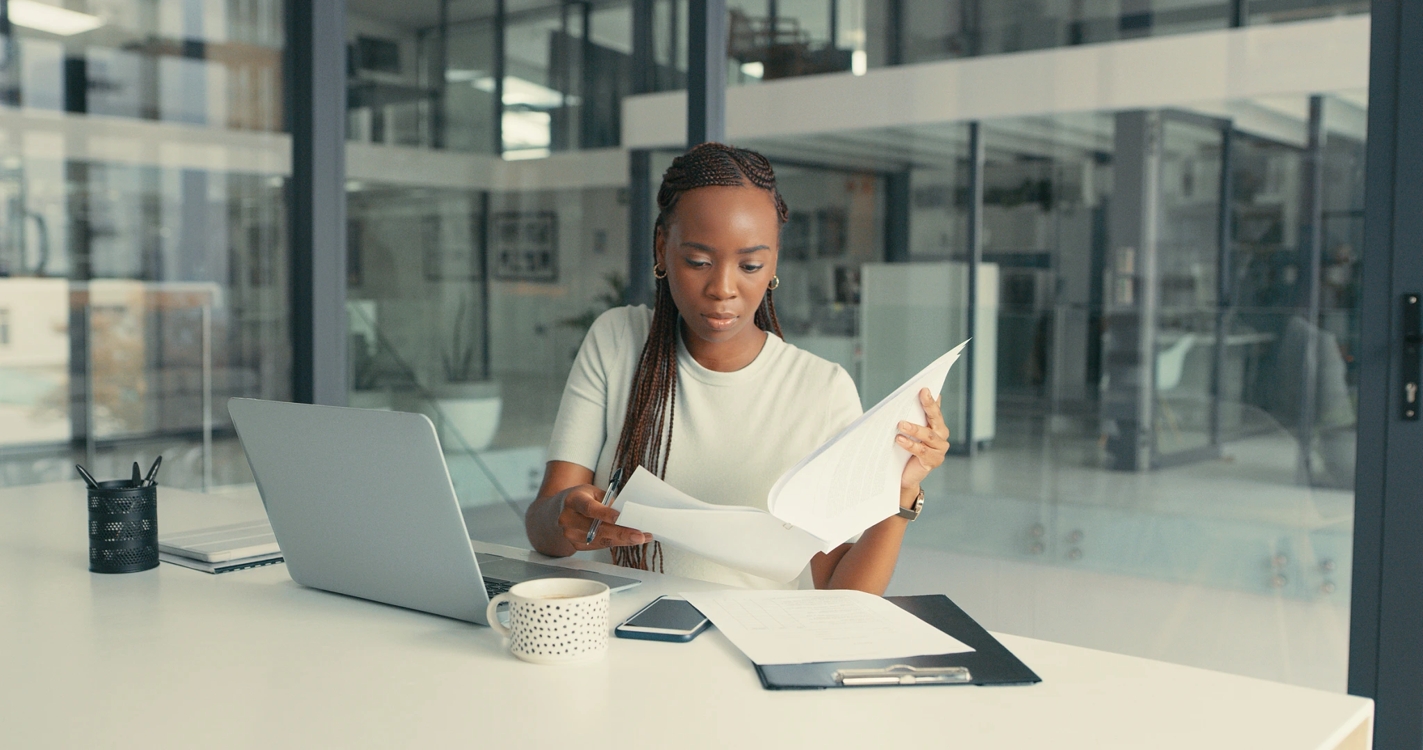 A woman sits at a table, working on a laptop surrounded by papers while reading b2b marketing insights