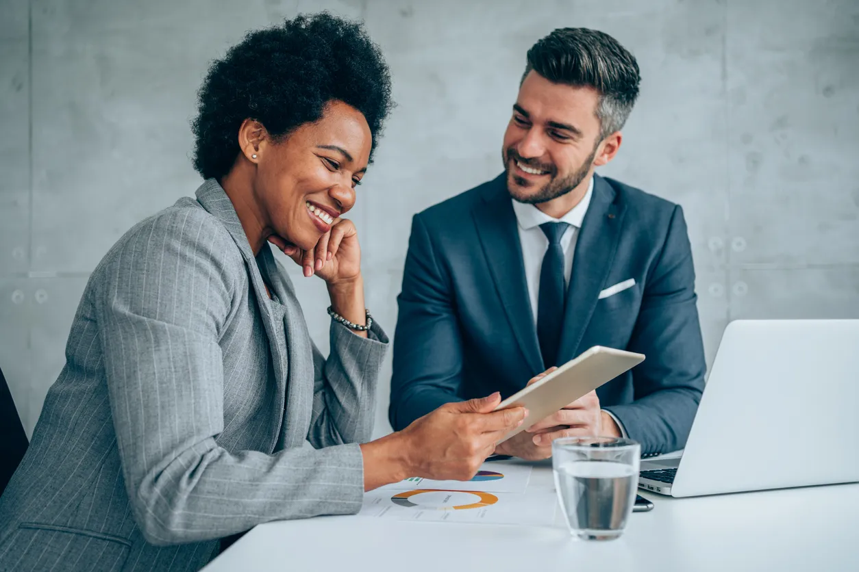 Two business professionals seated at a table, collaborating over a tablet device for b2b customer segmentation guide