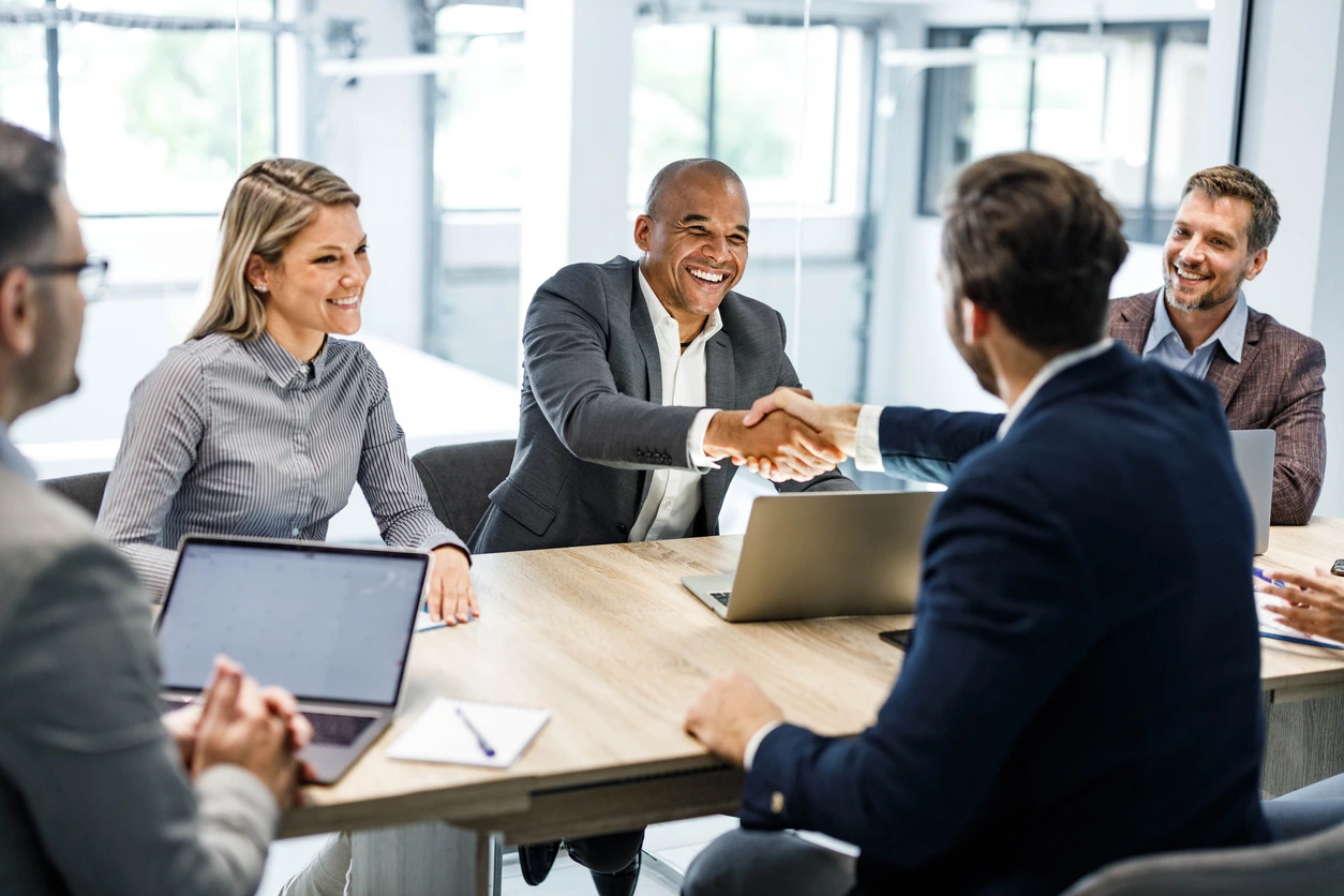 Business professionals shaking hands during a meeting, symbolizing agreement and collaboration on how to market b2b saas