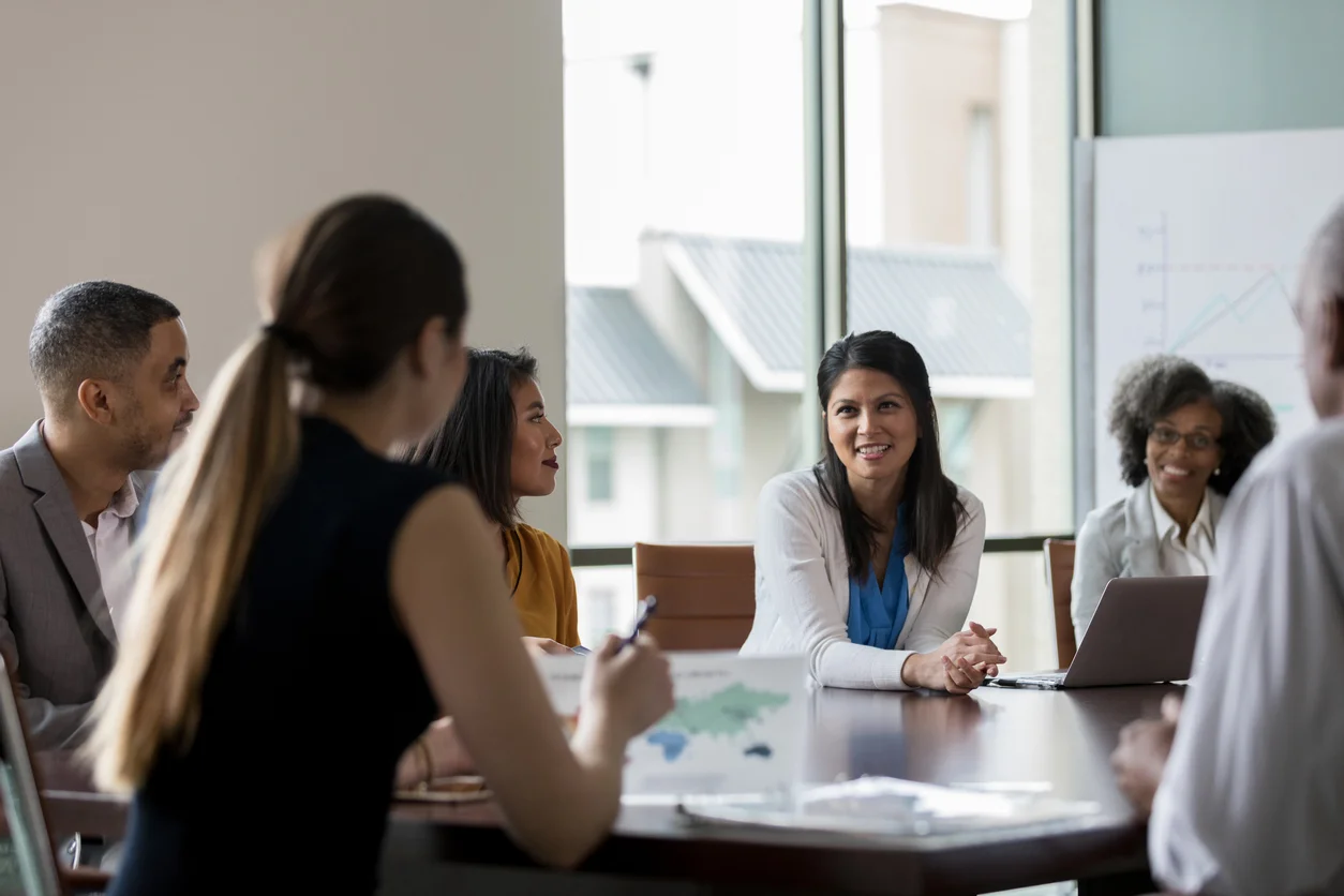 A diverse group of people engaged in discussion around a conference table during a meeting of b2b marketing capabilities
