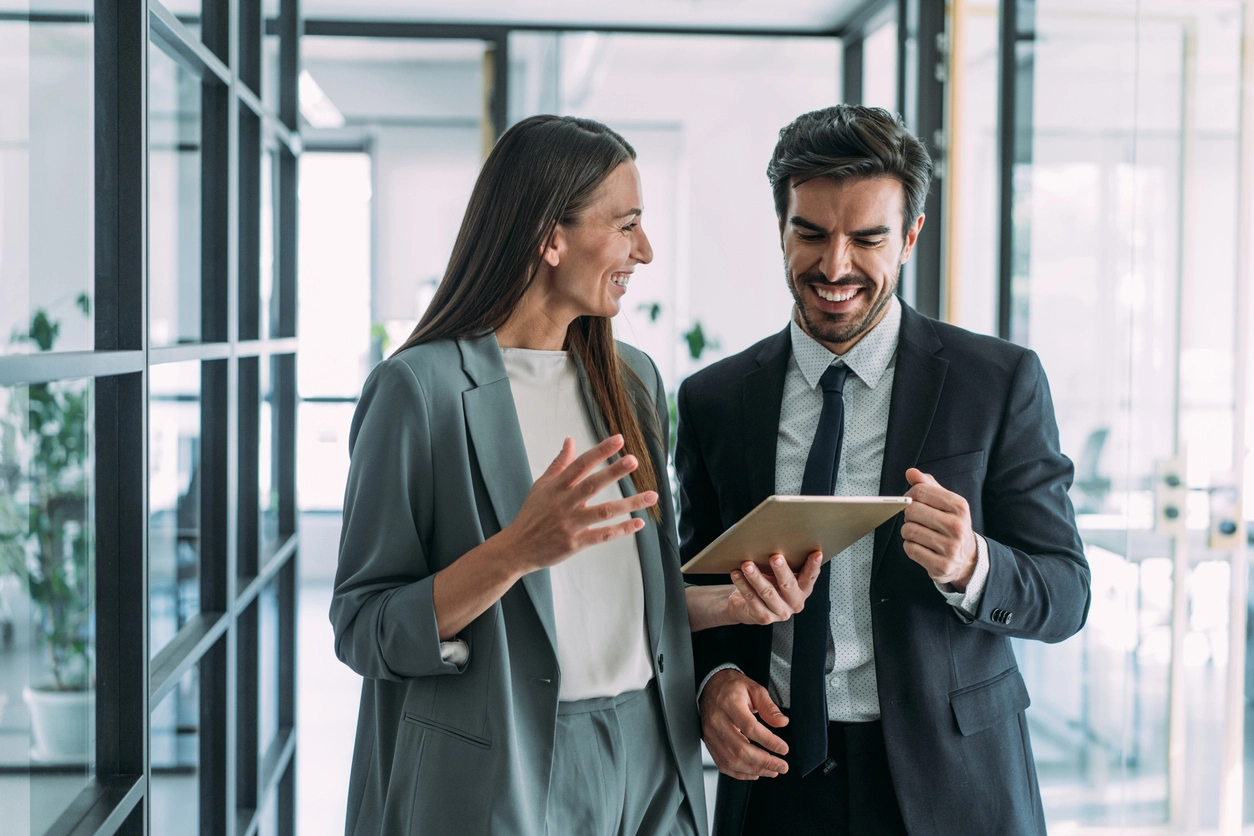 Two business professionals engaged in conversation while standing in a modern office setting for b2b digital marketing tactics