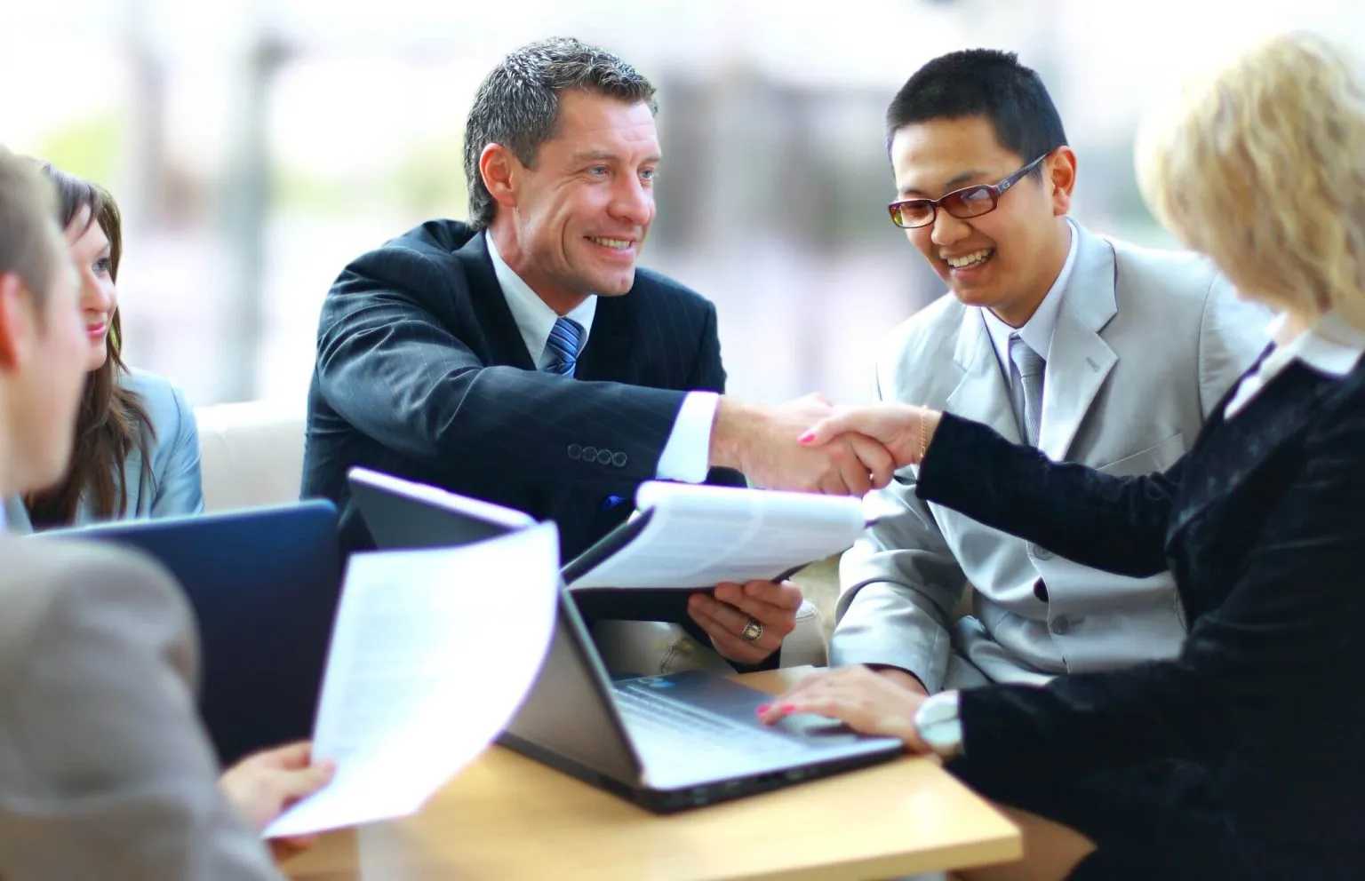 Business professionals shaking hands during a meeting, representing digital transformation in modern business.