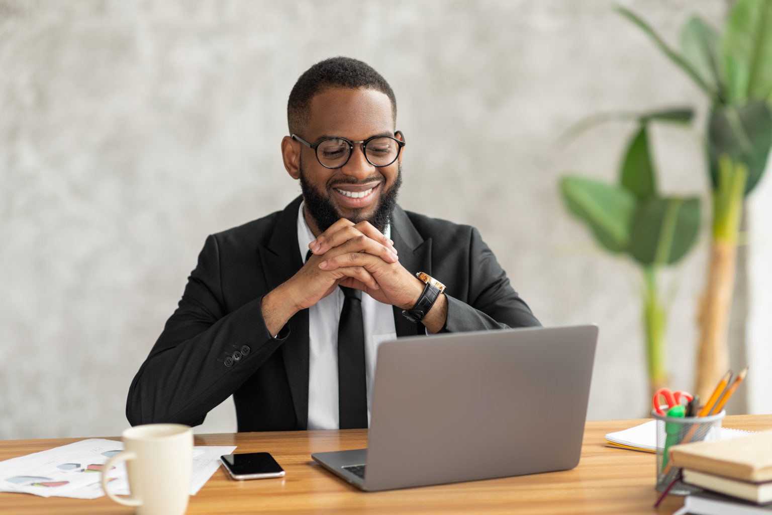 business man sits at desk with laptop and smiles after perfecting B2B email marketing