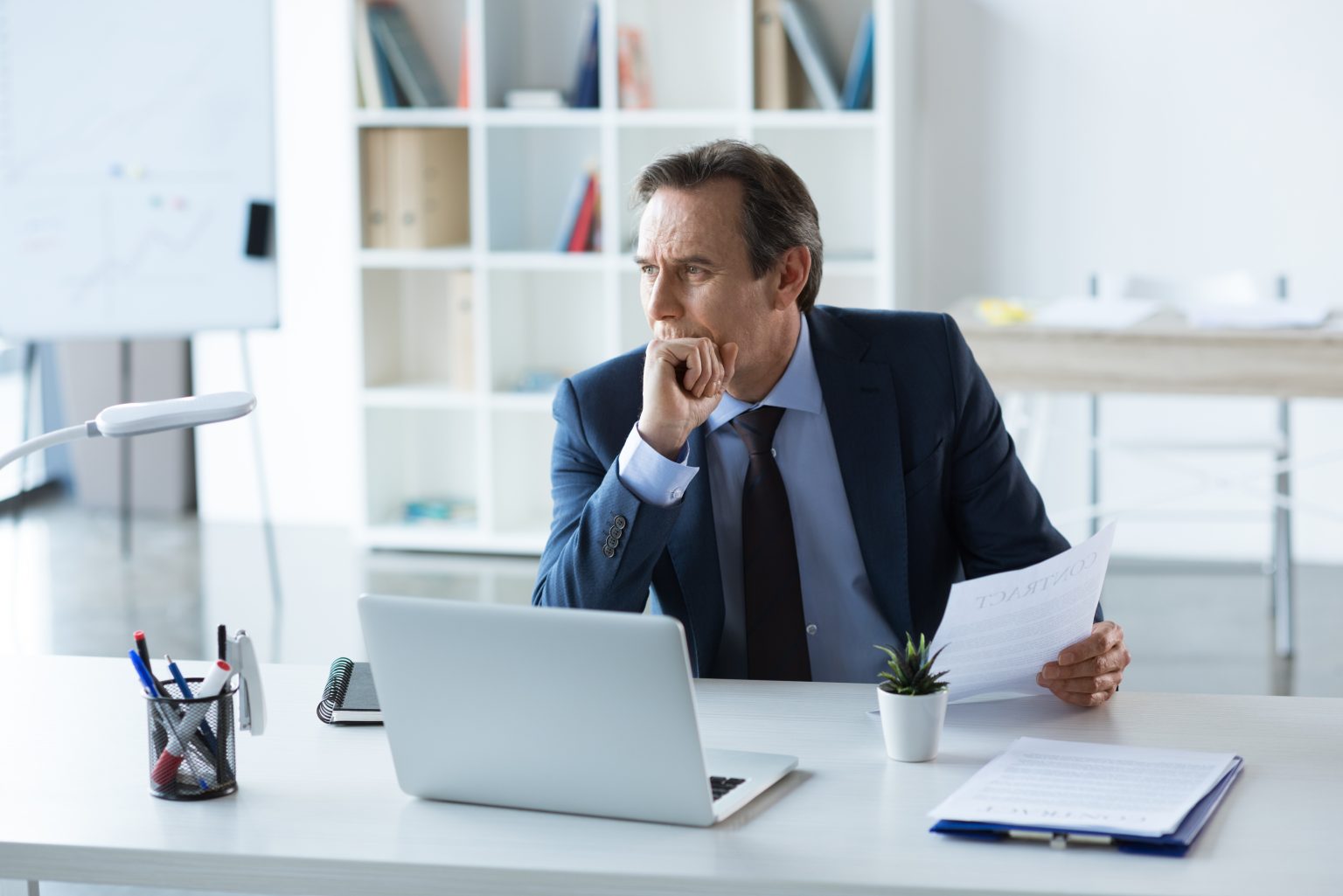 businessman sits at desk in office with laptop as he considers the b2b online marketplace