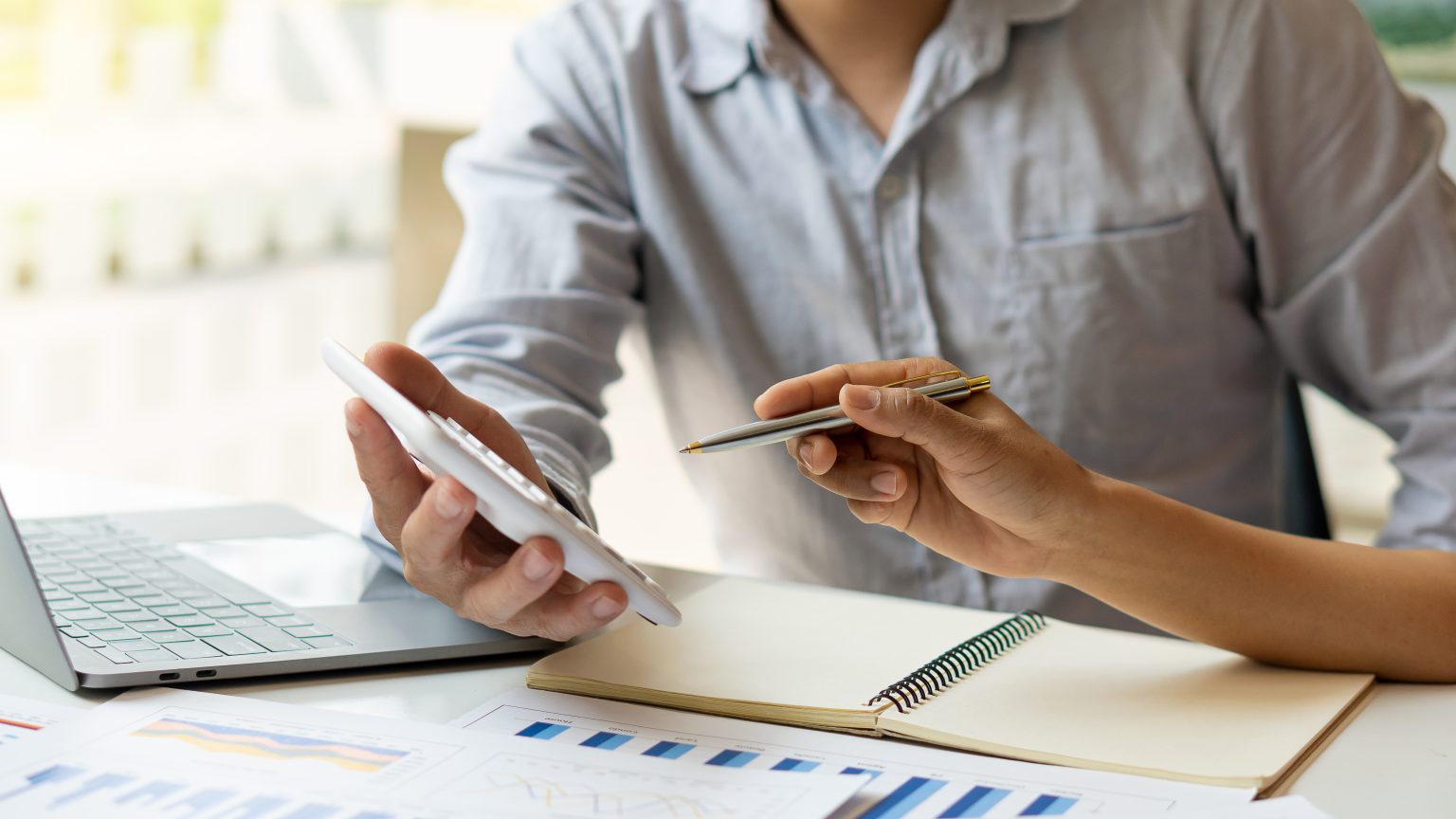 businessman calculates B2B sales KPIs with a calculator at a desk in an office setting