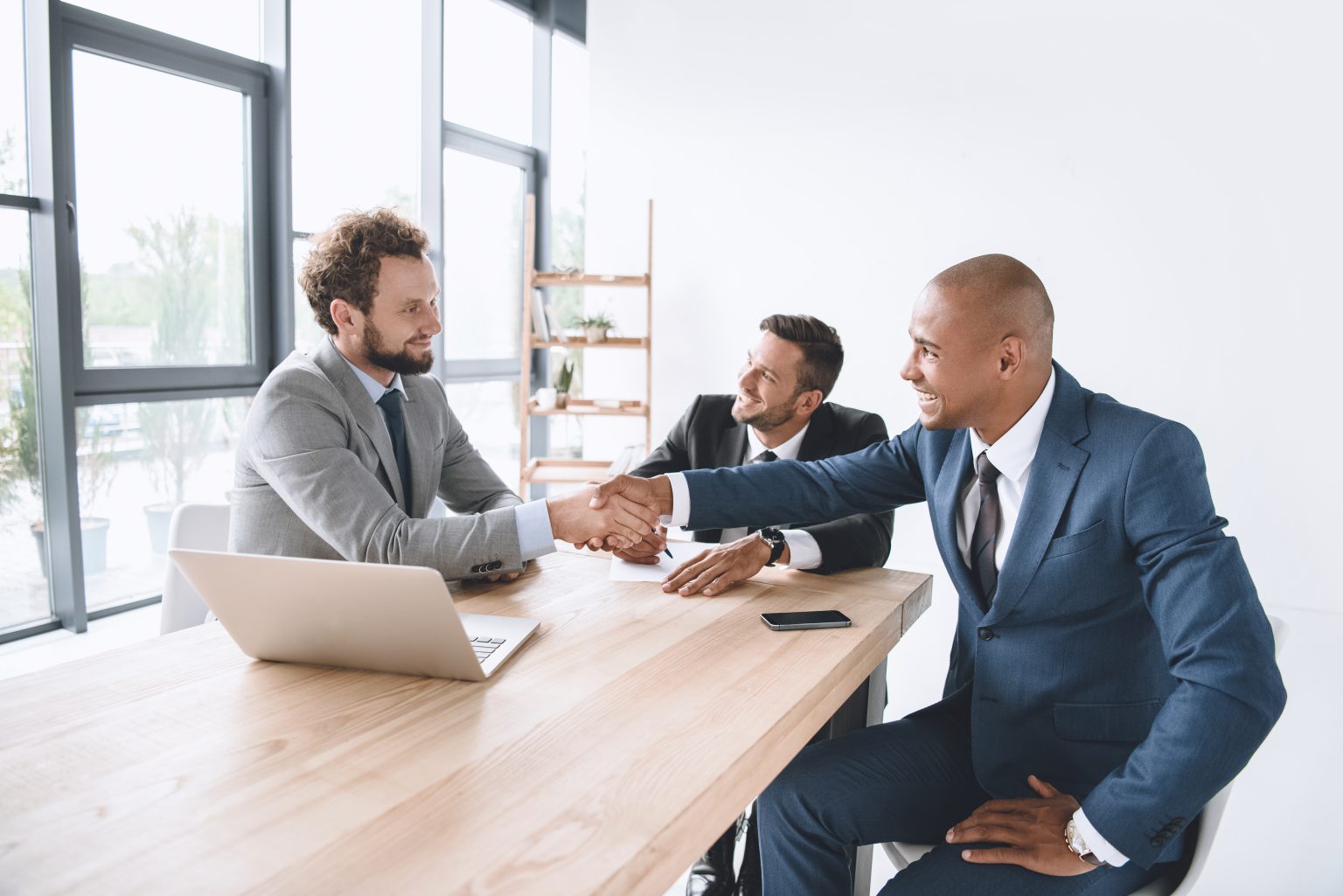 smiling businessman shaking hands at meeting in workplace after talking about brand personality