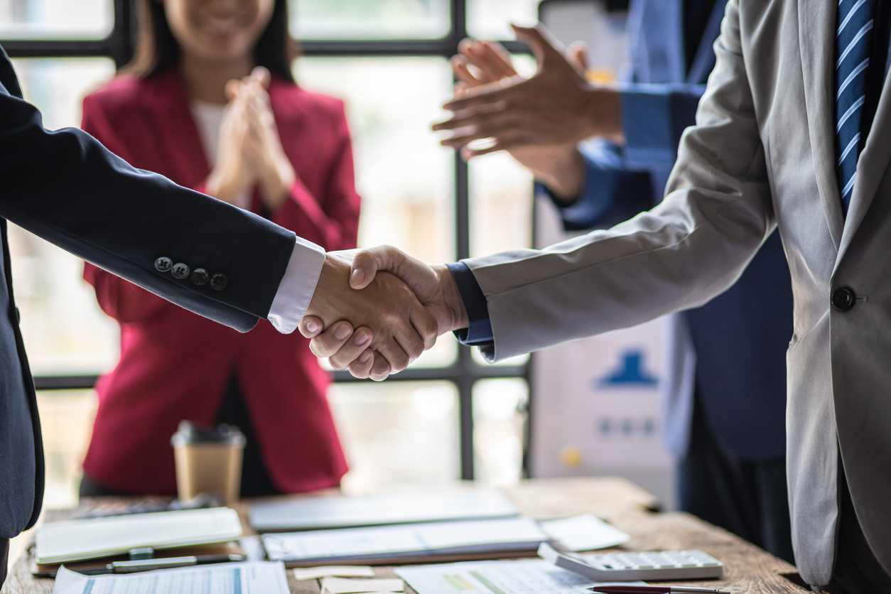 business builders collaborate and shake hands in office setting after a partner meeting