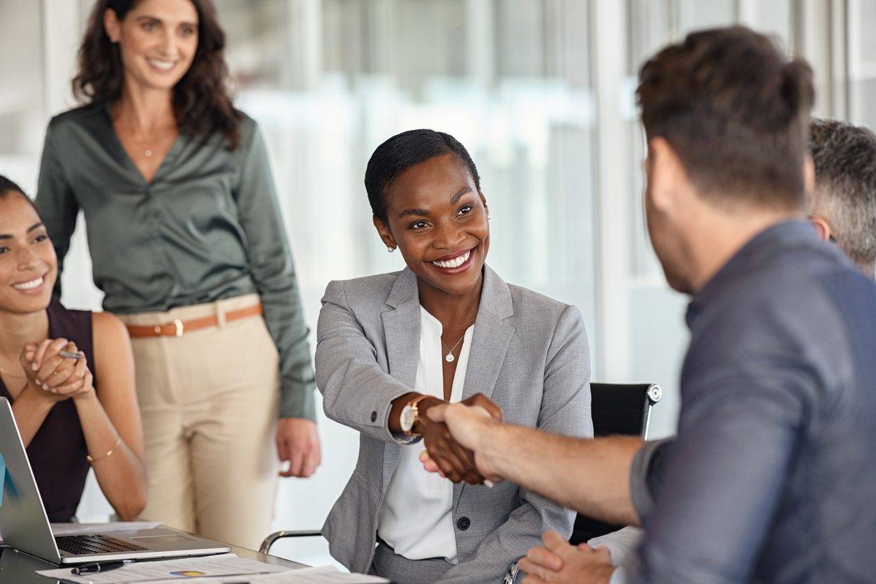 happy business woman shakes hands at meeting aftering using customer experience to drive growth