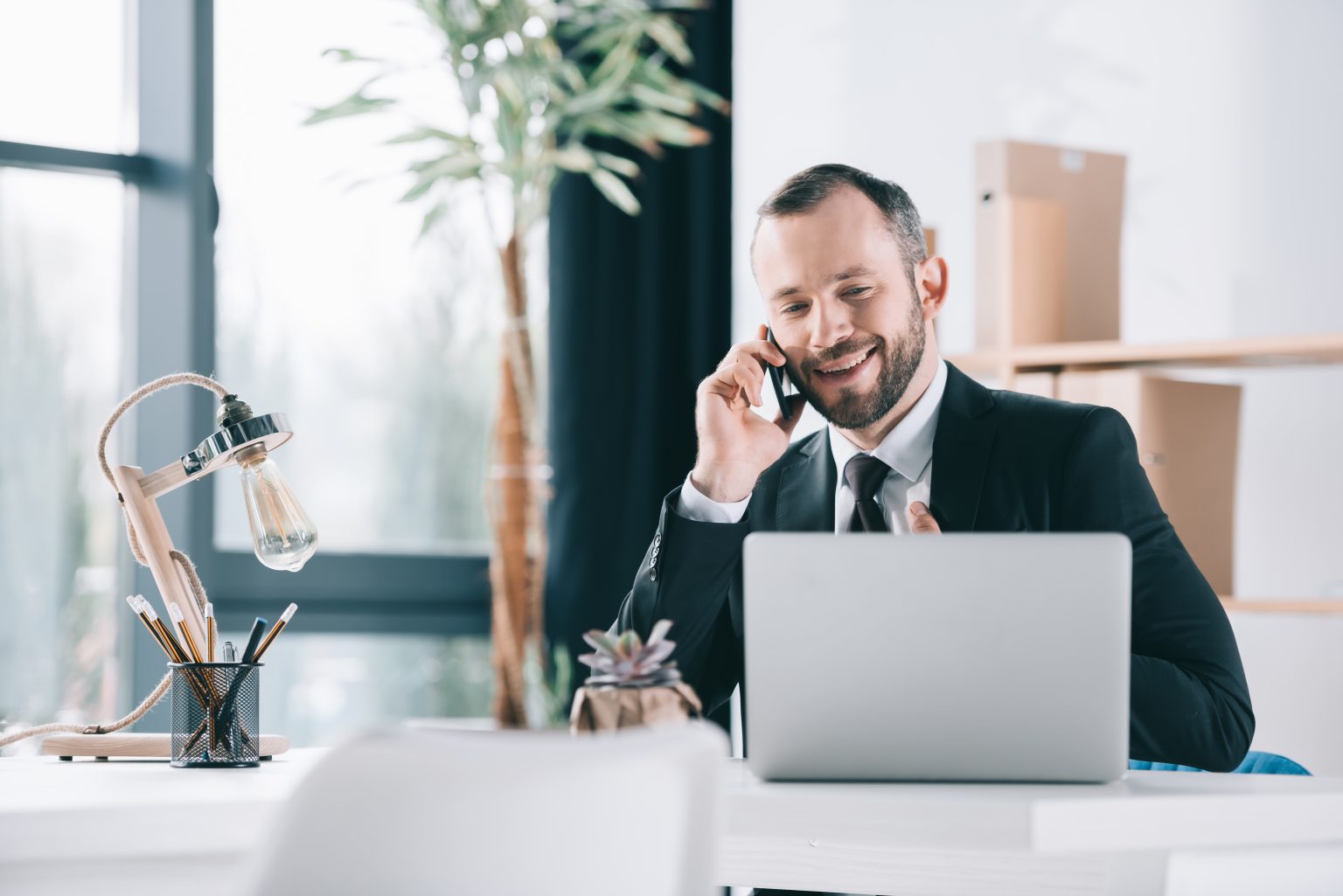 businessman sitting at his desk with computer and talking on the phone about how to choose marketing channels