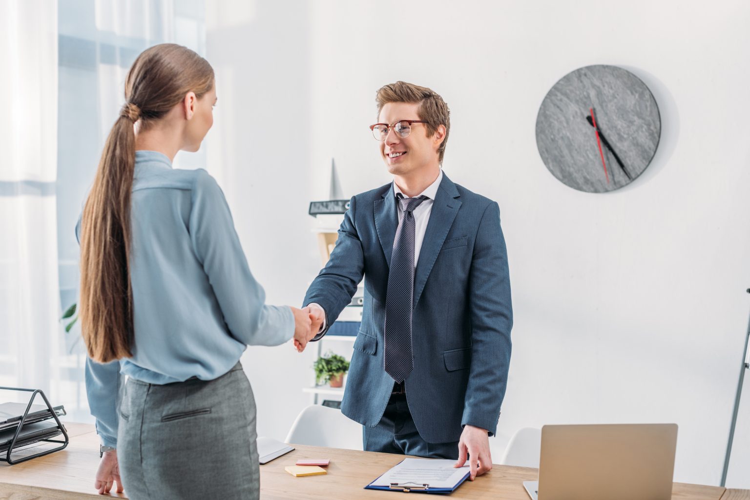 : businesswoman and businessman shaking hands in office to represent how industry leaders build customer-centric services for success