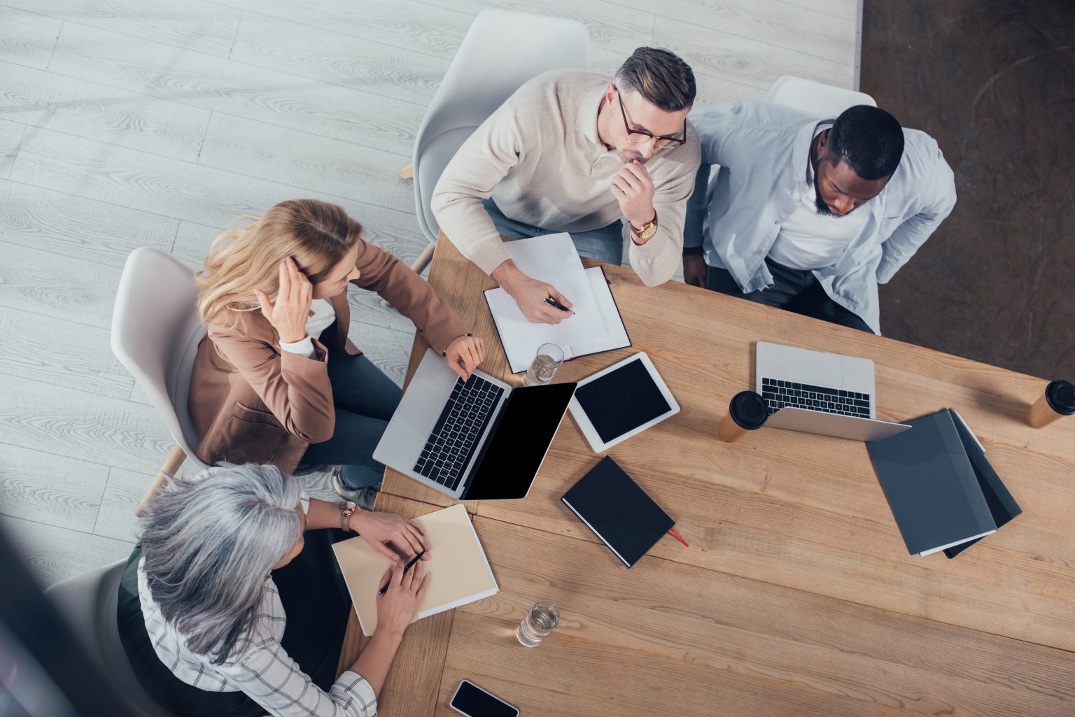 overhead view of colleagues talking and sitting at a table during a meeting about sales-marketing alignment