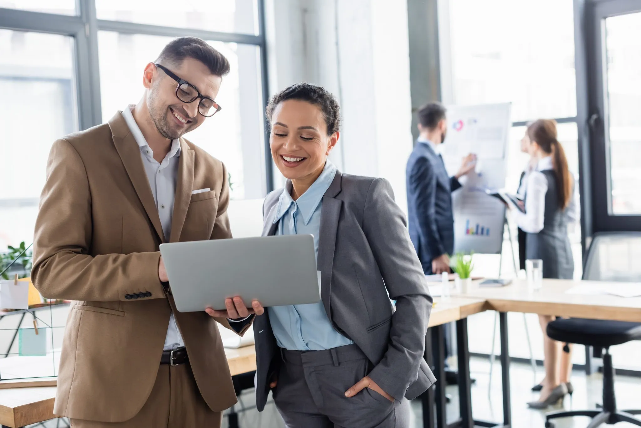 Business professionals reviewing data on a laptop in an office, representing marketing innovation and modern business strategy.
