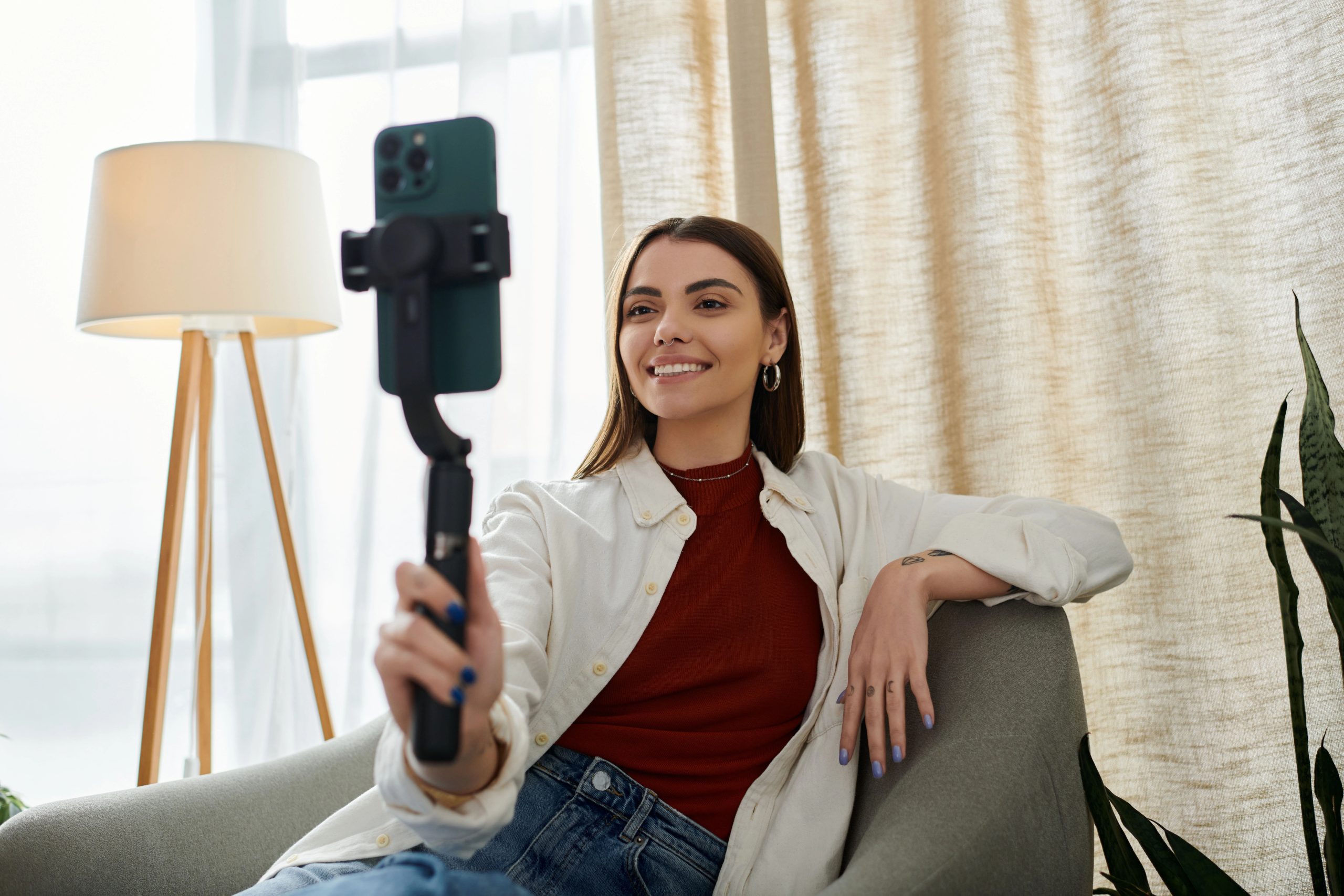 influencer holding phone and tripod in front of face while sitting on couch