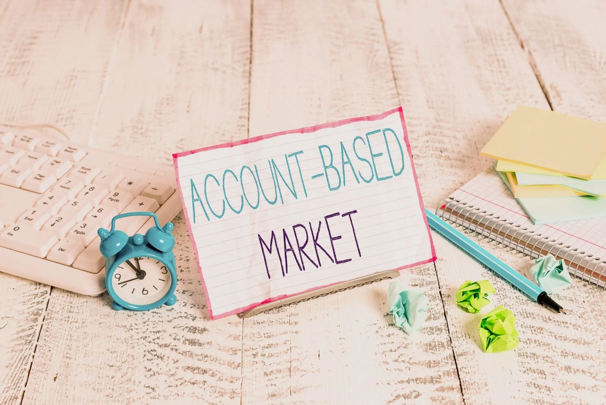 Account based marketing strategy concept displayed on a desk with a handwritten “Account Based Market” sign, planner, sticky notes, and office tools for targeted B2B growth.