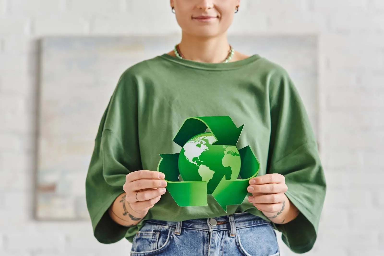 Person holding a recycling symbol with a globe, representing sustainability and environmental responsibility for sustainable product innovation