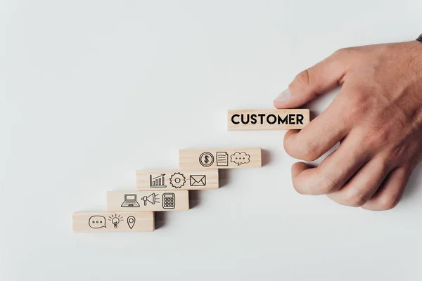 Hand placing a wooden block labeled “Customer” at the top of a staircase representing the customer journey for b2b relationship building in engineering