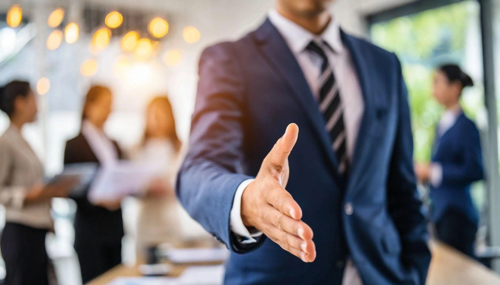 Businessman in a suit and tie shaking hands with two other professionals in a formal setting for best b2b marketing campaigns lessons