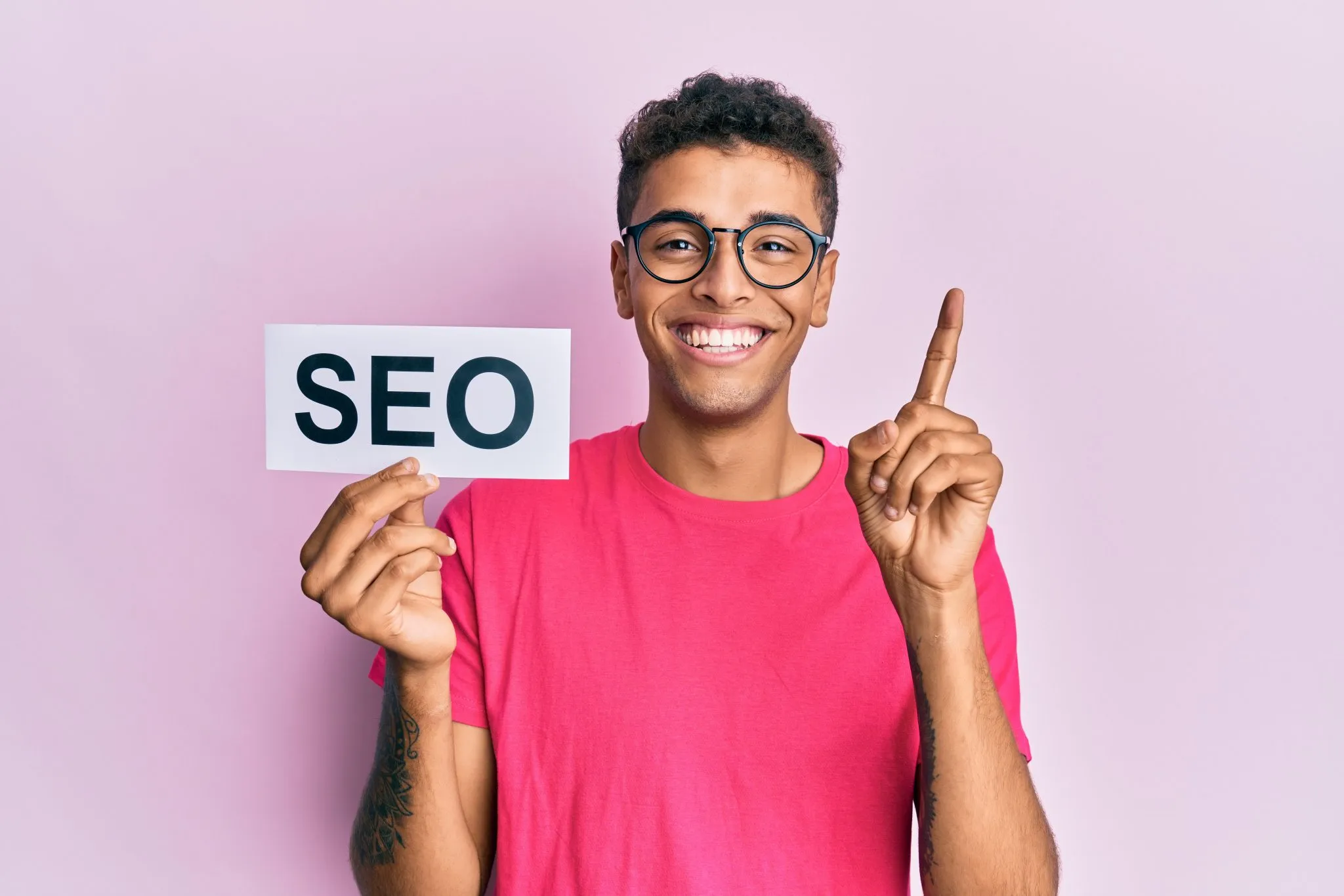 A man wearing glasses holds a sign that reads "SEO," emphasizing the importance of search engine optimization in state of seo 2025 ai analytics