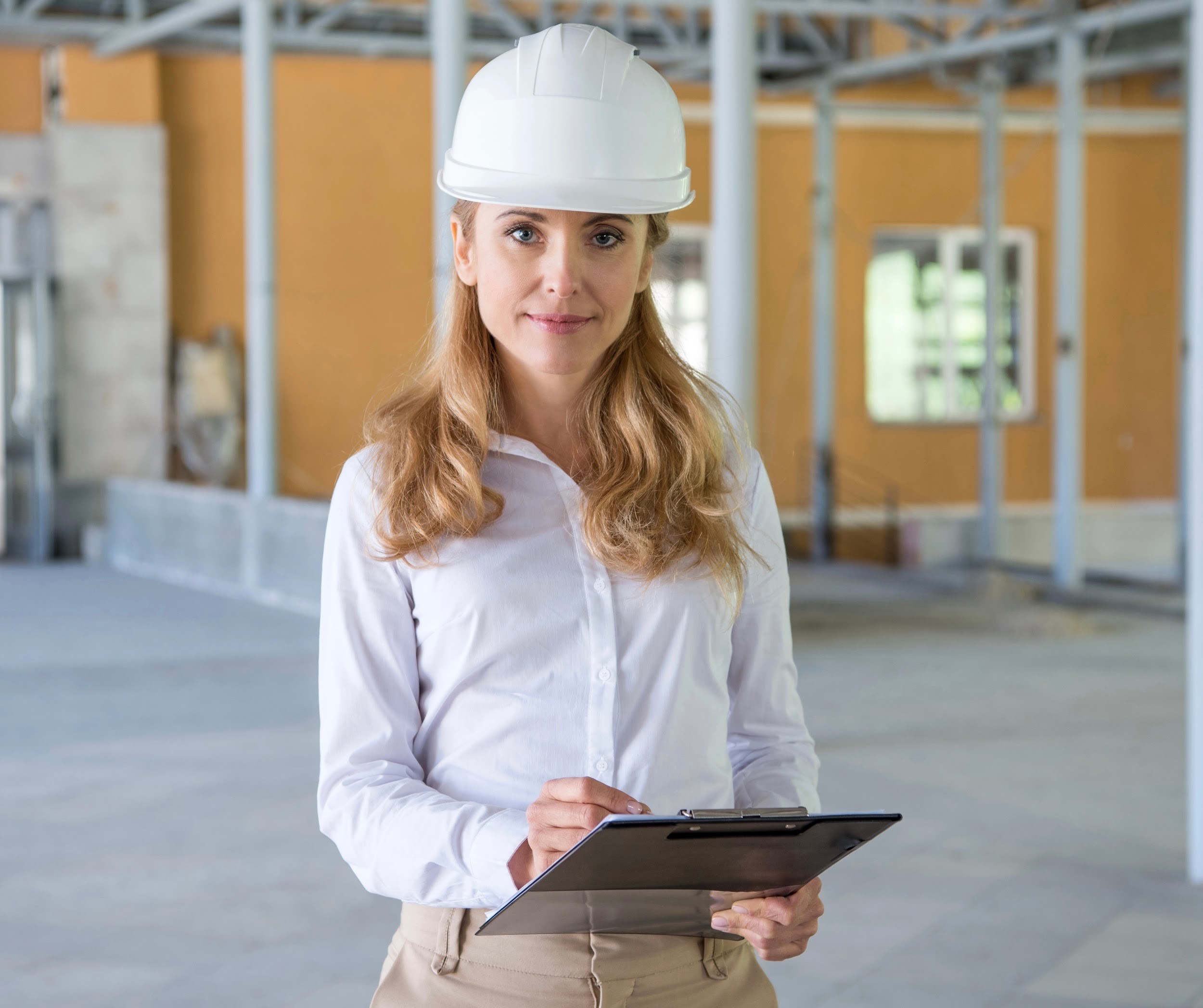 woman in construction gear writing on clipboard