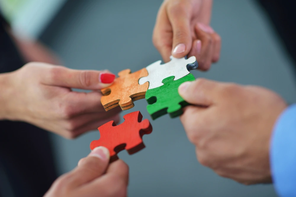 Business professionals collaboratively fitting puzzle pieces together, symbolizing teamwork and problem-solving of b2b partnership strategy