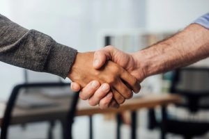 cropped view of businessman shaking hands with colleague in office
