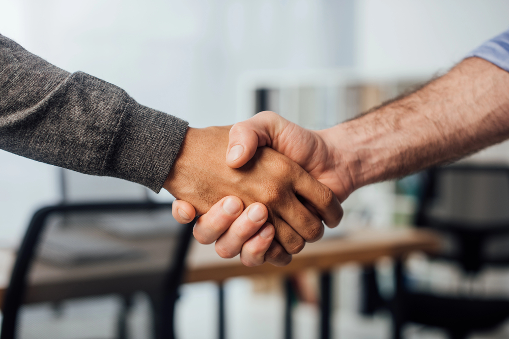 cropped view of businessman shaking hands with colleague in office