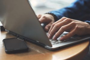 close up of hands typing on laptop searching for information on AI-powered SEO